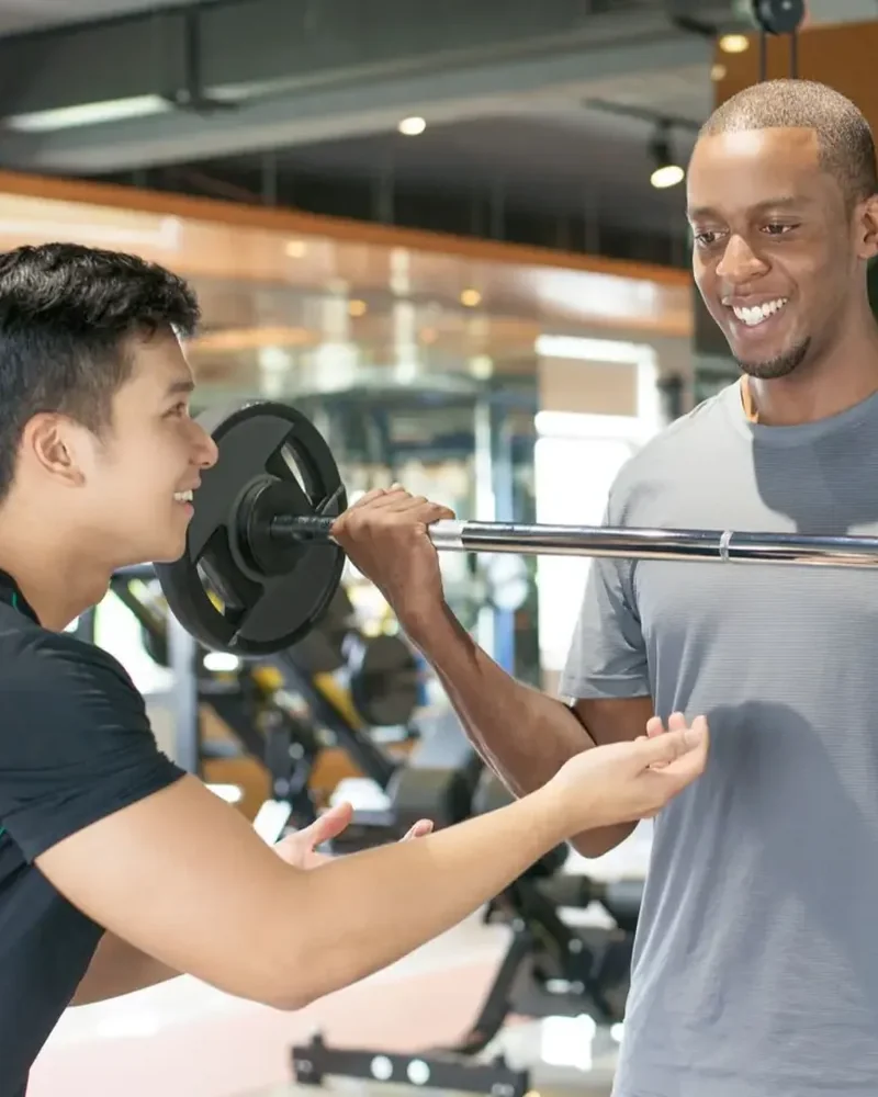 Therapist spotting a patient during a barbell strength exercise